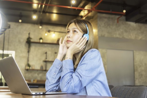 年轻女子喜欢在家里的客厅里听音乐，放松身心。生活方式的概念图片下载