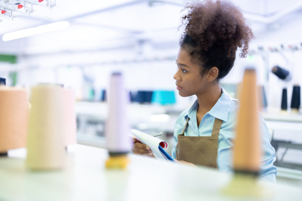 一位美国女设计师作为一名女裁缝，在一个大型缝纫工业中使用计算机化的机器进行生产并出口到世界市场和百货公司的勤奋工作。图片下载