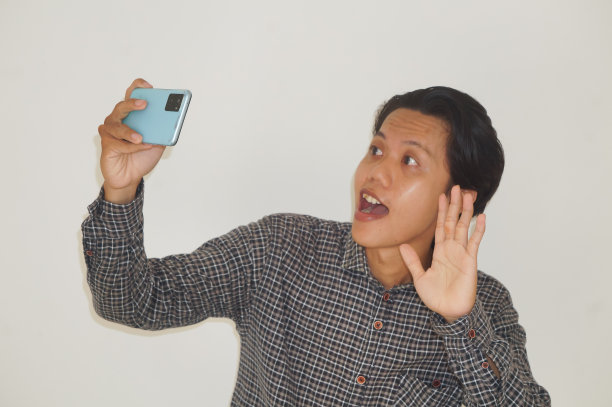 一名快乐的亚洲年轻人穿着黑色衬衫，用手机自拍，并在社交网络上发布了一张照片图片下载