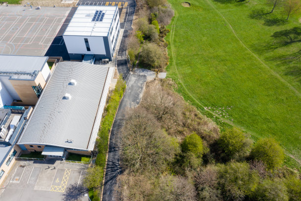 这是英国西约克郡利兹比斯顿村的航拍照片，在秋天的时候，无人机从树木繁茂的地区看到了一所学校的建筑图片下载