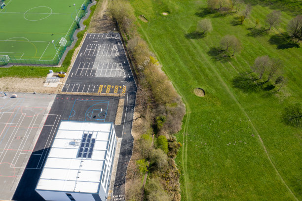 这是英国西约克郡利兹比斯顿村的航拍照片，在秋天的时候，无人机从树木繁茂的地区看到了一所学校的建筑图片下载