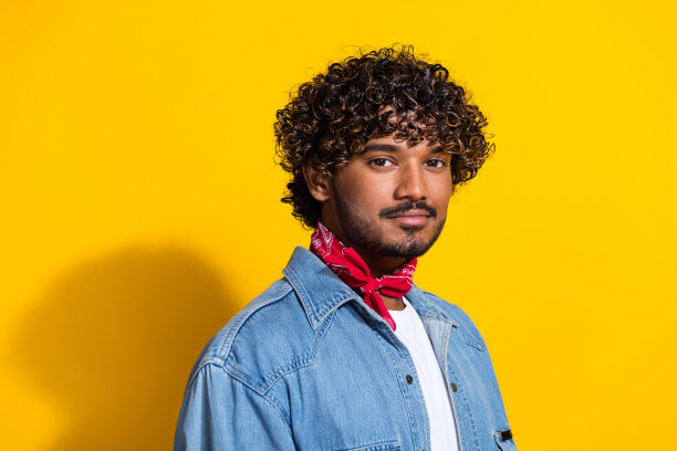 照片中帅气的年轻人的肖像购物模特海报穿着时髦的牛仔服装红色围巾孤立在黄色的背景图片下载