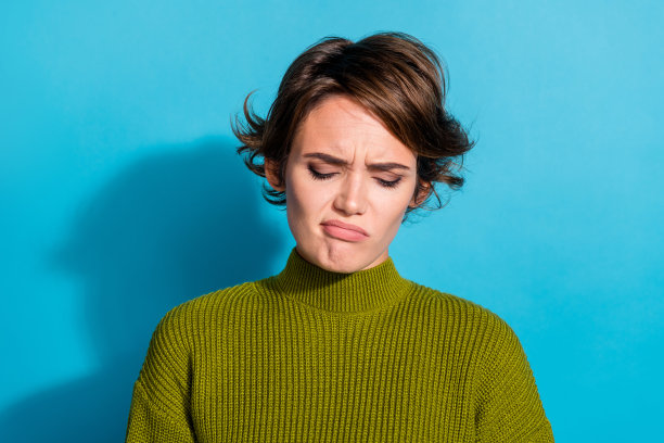 照片中悲伤沮丧的女孩穿着卡其色的衣服，糟糕的情绪冲突，烦恼孤立在青色的背景上图片下载