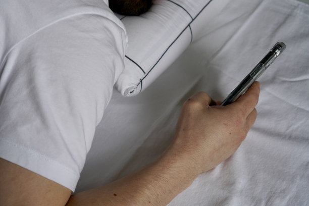 一个人睡前在床上玩手机的照片图片下载