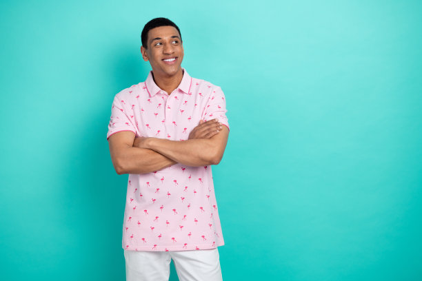 照片中聪明的创意男子双手交叉，露出牙齿的微笑，在蓝绿色的背景上看起来空无一物图片下载