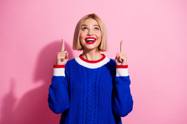 照片惊讶有趣的女人金发，她喜欢护发产品，手指指着头顶，空白的空间孤立在粉红色的背景图片下载