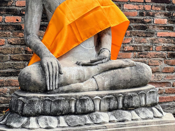 一个人坐在石基上的雕像的照片。图片下载