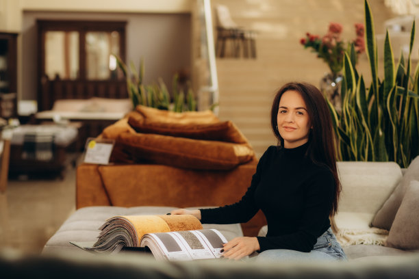 女士选择沙发的布料。一位年轻女性在看组织样本。选择沙发的颜色。纺织行业背景。组织目录。高质量照片图片下载