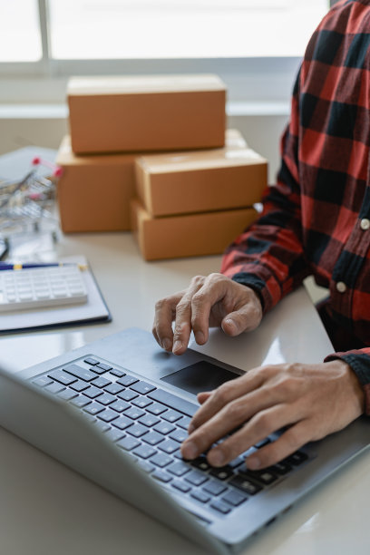 小型企业企业家，中小企业，独立男性，在家工作。使用智能手机和笔记本电脑进行商业考察在线营销中小企业包装盒概念电子商务团队的特写照片图片下载