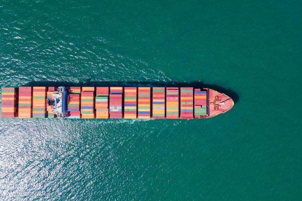 这张照片提供了一个令人惊叹的鸟瞰图，展示了一个繁忙的货船港口，大型船只在这里停靠并卸下珍贵的货物。图片下载