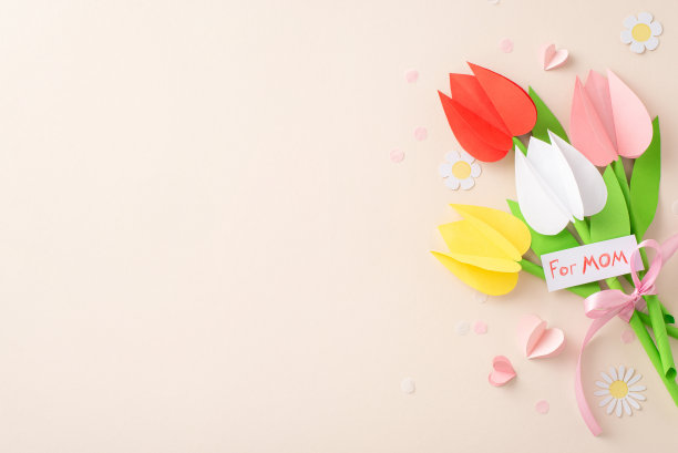 用爱精心制作母亲节的情怀。俯拍的照片上有折纸花，卡片上写着“给妈妈”，旁边是精心制作的花束，心形图案，柔和的米色背景上的软纸屑，还有广告的空间图片下载