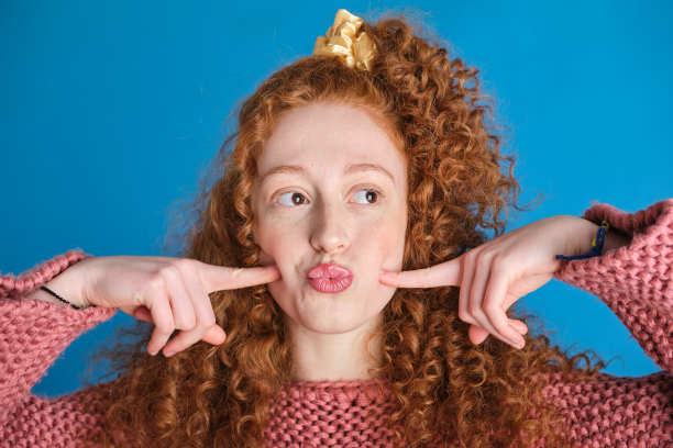 正面照片是一位美丽自信的西班牙白人年轻女性，她有着卷曲的长发，目光转向侧面，做着有趣的表情图片下载