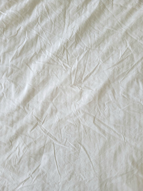 白色皱巴巴的床单。早上的特写照片图片下载