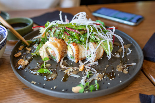 灰色陶瓷盘子里的寿司卷和沙拉。盘子上乱七八糟的，未经处理的普通日常膳食照片图片下载