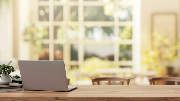 在阳光明媚的日子里，客厅里的木桌上放着一台笔记本电脑，可以看到美丽的花园景色。图片下载