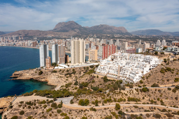 这是西班牙贝尼多姆北部的无人机照片，阳光明媚的夏天，海边的岩石小径和高层公寓。图片下载