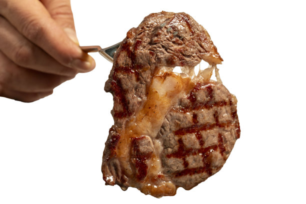 新鲜烤牛肉肠牛排孤立在白色背景。他用叉子拿着一片肋眼肉。高质量的照片。近距离图片下载
