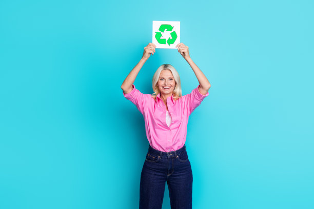 可爱的高级女士的照片肖像提高回收标志穿着时尚的粉红色智能休闲服装孤立的海蓝宝石色背景图片下载