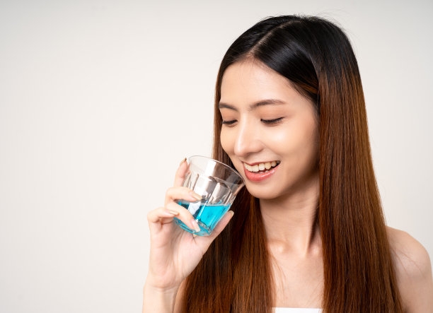 年轻的亚洲女性用漱口水来保持牙齿的健康。用漱口水清洁口腔，保持口腔健康。图片下载