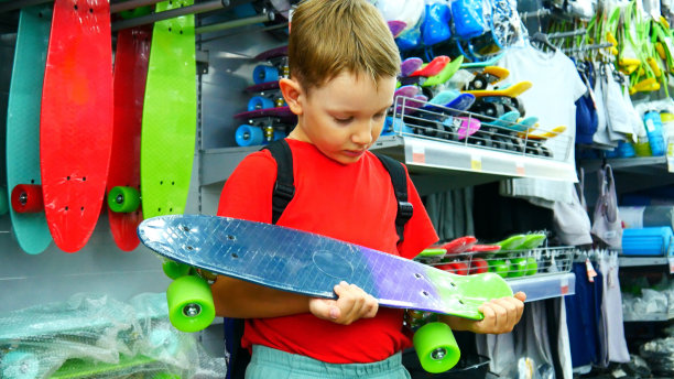 一个可爱的男孩在体育部检查他手中的滑板图片下载