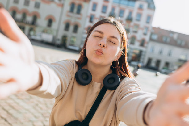照片轻松迷人积极的年轻女子拿着相机，在市中心户外自拍夏天。旅游度假理念的生活方式。观点。图片下载
