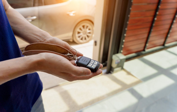 年轻人用遥控器打开现代别墅的自动滑动前门图片下载