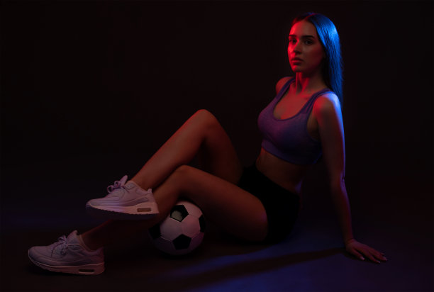 一个穿着短裤和上衣的美丽苗条的女运动员踢足球图片下载