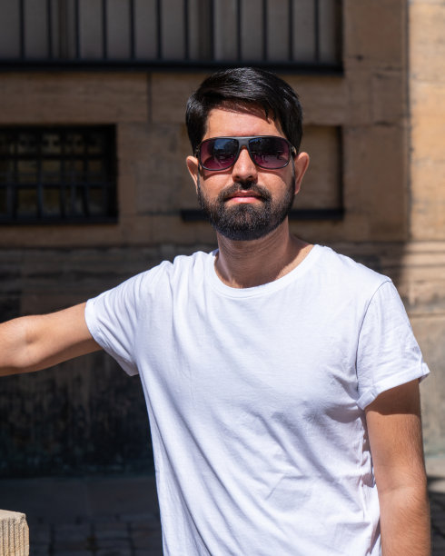 一个留着黑胡子，穿着浅色衣服，戴着墨镜的现代巴基斯坦男人的特写图片下载