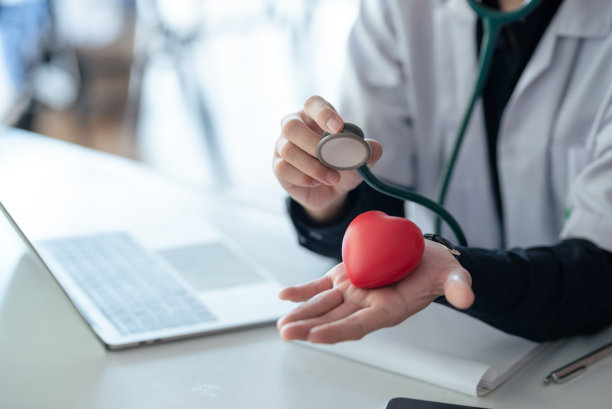 医生拿着听诊器和一颗红心。医疗保健和心脏病学概念。图片下载