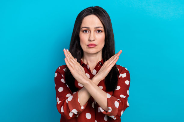 严肃自信的黑发女孩的肖像，穿着红色衬衫，双臂交叉，在蓝色背景上说停止孤立图片下载