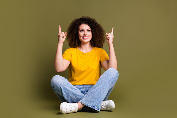 可爱有趣的女人的全身大小的照片直接手指广告牌上面的标语公司孤立的卡其色背景图片下载