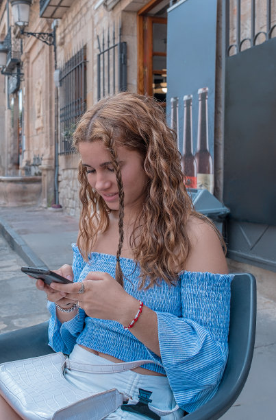 年轻的女孩用她的手机娱乐。图片下载