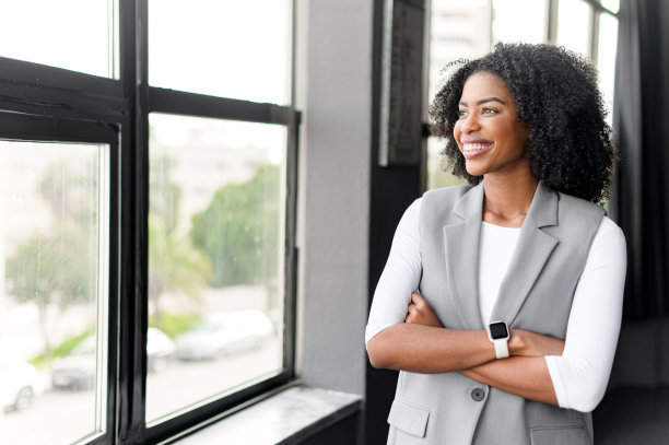 女商人站在窗前沉思，双臂交叉，望着窗外的城市图片下载
