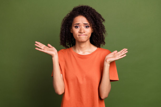 照片中，年轻漂亮的女孩不开心地耸耸肩，困惑地穿着时髦的橙色衣服，孤立在卡其色的背景上图片下载