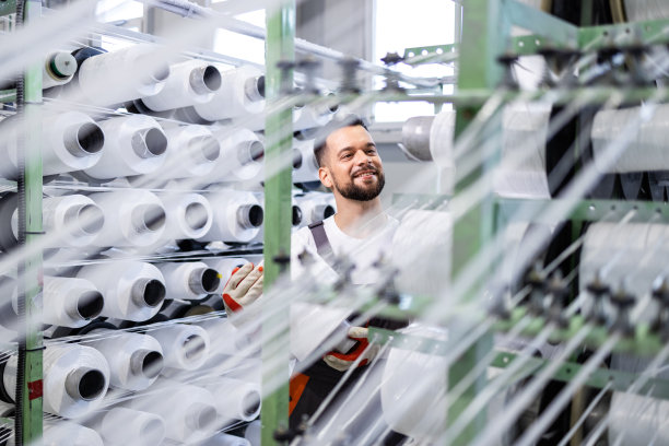 经验丰富的纺织工厂工人在工业针织机上更换线芯。图片下载