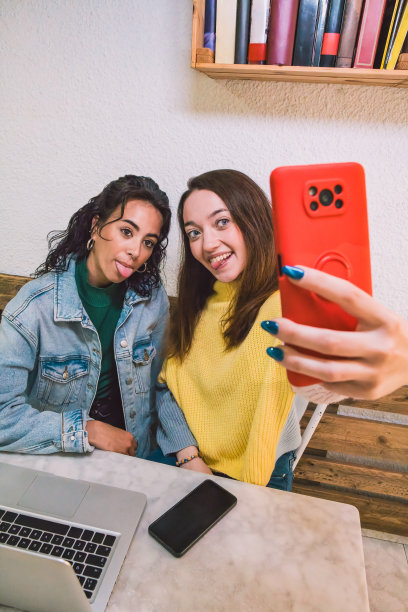 两个不同种族的朋友用他们的手机拍了一张照片。图片下载