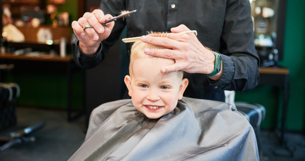 可爱的小男孩在理发店理发。图片下载