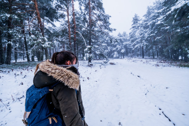 个人资料照片拍摄了一名女子在高耸的松树和白雪覆盖的景观中徒步旅行。图片下载