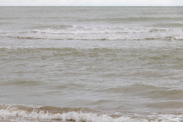 大海的小波浪的照片，从一个角度看在眼睛水平。水呈灰色，略带棕色图片下载