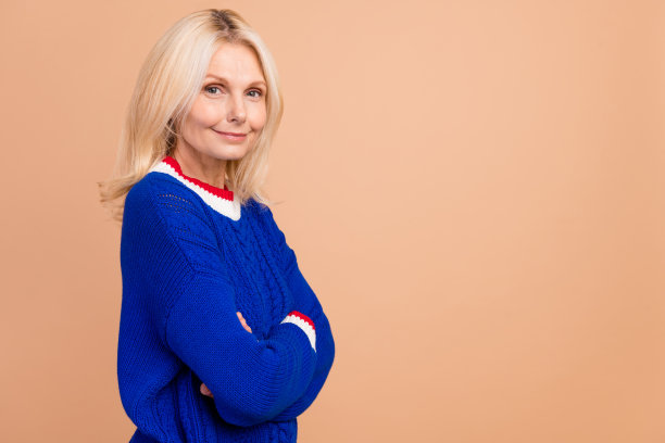 照片中心情好的人，金发碧眼，穿着蓝色套头衫，手掌折叠，靠近米色背景上孤立的空白空间图片下载