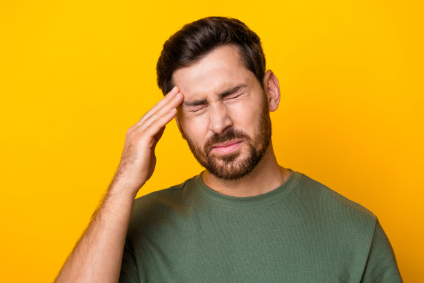 压力抑郁的家伙穿着绿色t恤手臂头感觉疼痛孤立黄色背景的照片图片下载