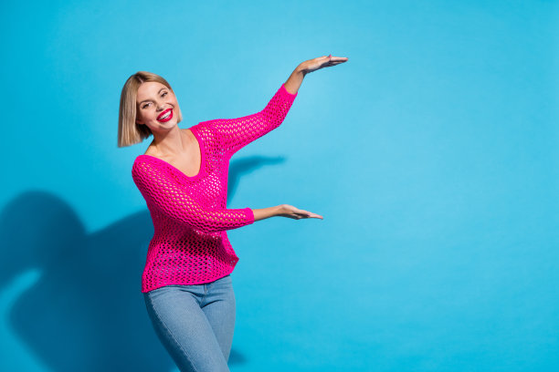 照片肖像可爱的年轻女士双手显示测量身高穿着时尚的粉红色针织服装孤立在蓝色背景图片下载