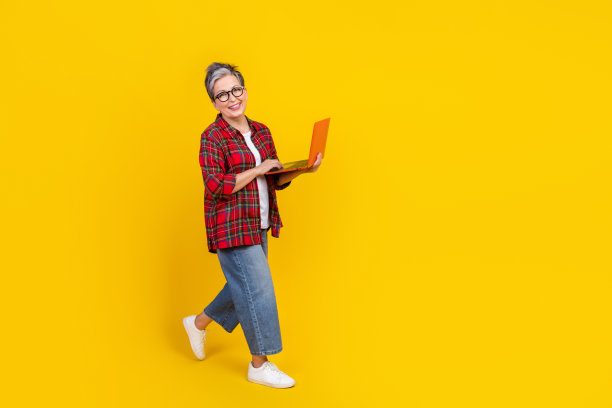 迷人的人的全身侧面照片用笔记本电脑走空空间孤立在黄色的背景图片下载