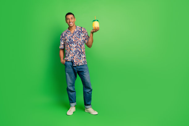 正面好人手持菠萝鸡尾酒的全长照片，空白空间孤立在绿色背景上图片下载