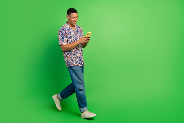 照片正面迷人的时尚男子走在街上聊天分享短信5g连接空白空间隔离绿色背景图片下载