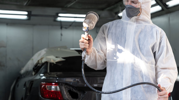 汽车服务人员在防护罩涂装车身。Oxus图片下载