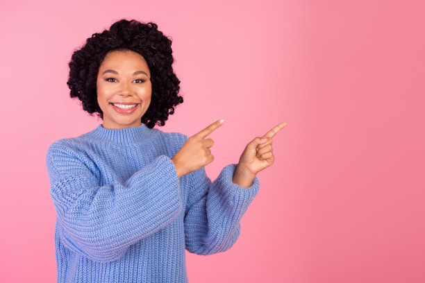 可爱的年轻女士的照片肖像点促销空穿着时尚的蓝色针织服装孤立在粉红色的背景图片下载