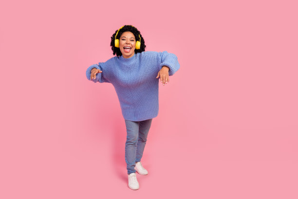 可爱的年轻女士跳舞的全身照片听音乐耳机穿时髦的蓝色针织服装孤立在粉红色的背景图片下载
