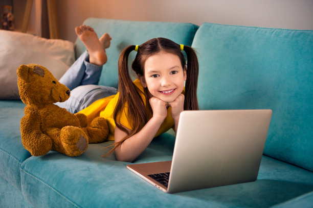 可爱小女孩的照片肖像躺在沙发上休息看电影卡通穿着时髦的黄色衣服现代娱乐室内部图片下载
