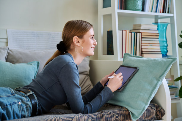 年轻的女青少年用数码平板电脑，手写笔在家里画画图片下载